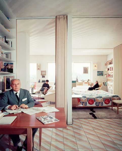 Architect Gio Ponti (with his wife and daughter in the background) in the Milan apartment he designed on Via Giuseppe Dezza.